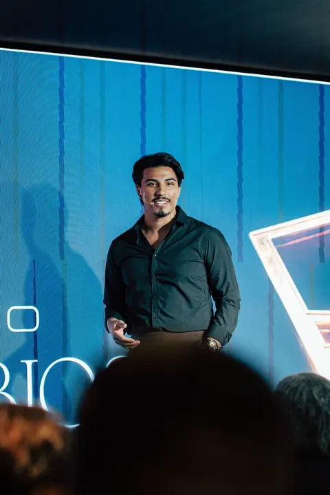 Palestrante no palco com painel azul do Projeto Provérbios