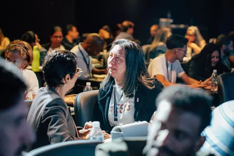 Participantes conversando em mesas do evento