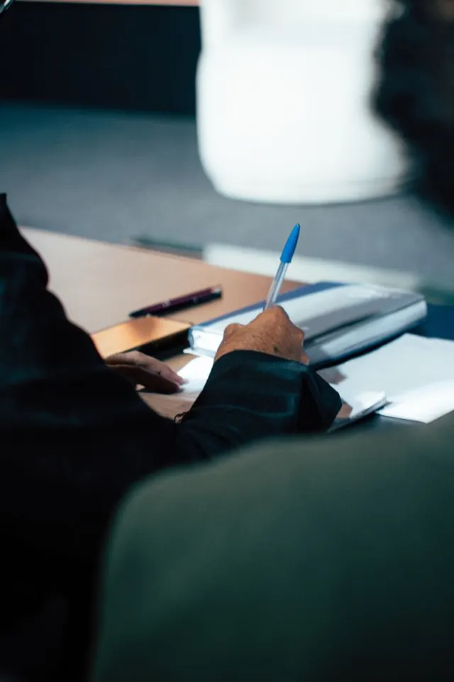Mão com caneta sobre caderno de anotações